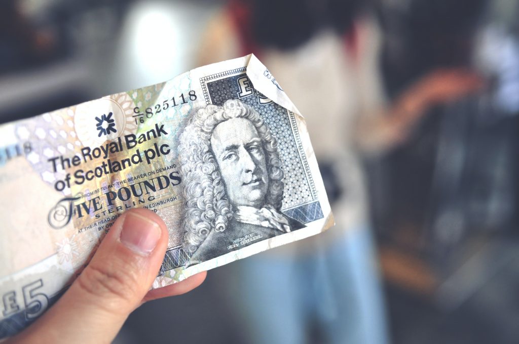 A Thumb holdinga scottish five pound note